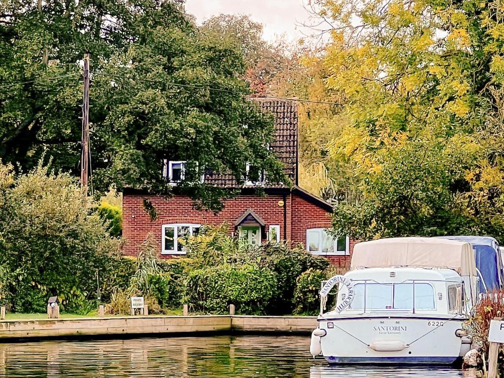 a boat in the water in front of a house at Norfolk Broads And Coast, Malthouse Cottage in Ranworth