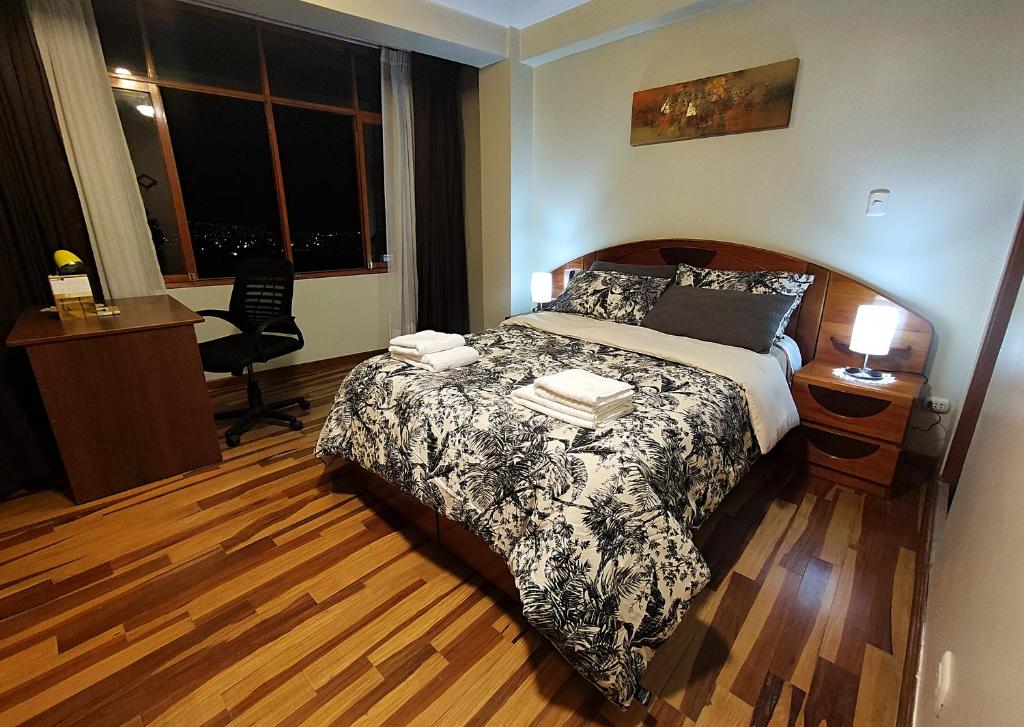 1 dormitorio con cama, escritorio y ventana en El Balcón del Sol, en Cusco