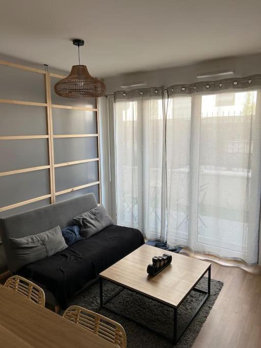 ein Wohnzimmer mit einem Sofa und einem Couchtisch in der Unterkunft L’appartement du bonheur in Colombes