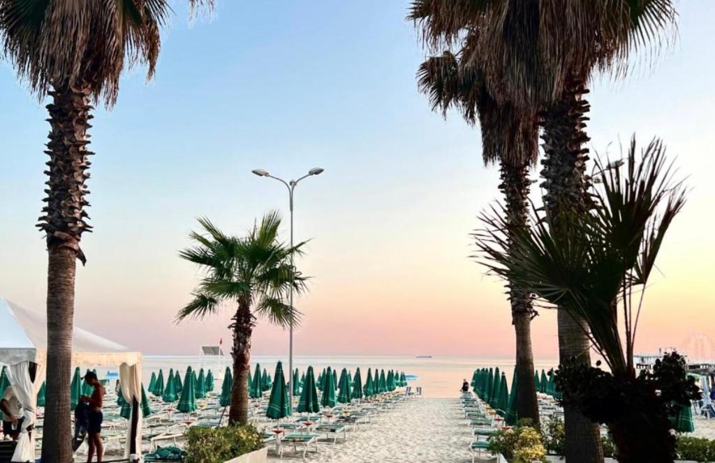 una playa con palmeras y sillas y el océano en Ervis beach apartment 5 minutes walking apartment-beach ONLY 2 NIGHS ORE MORE, en Durrës