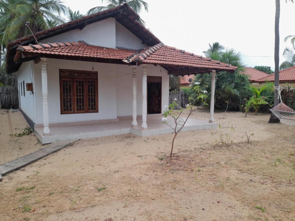 a small white house with a red roof at Rosa Kusum Vacation Home Near Kudawa Beach In Kalpitiya in Kalpitiya