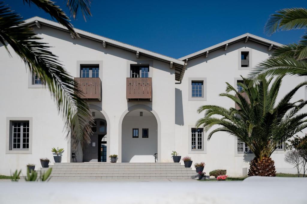 uma casa branca com palmeiras em frente em Villa Clara, Résidence face à l'océan et au golf de Chiberta em Anglet