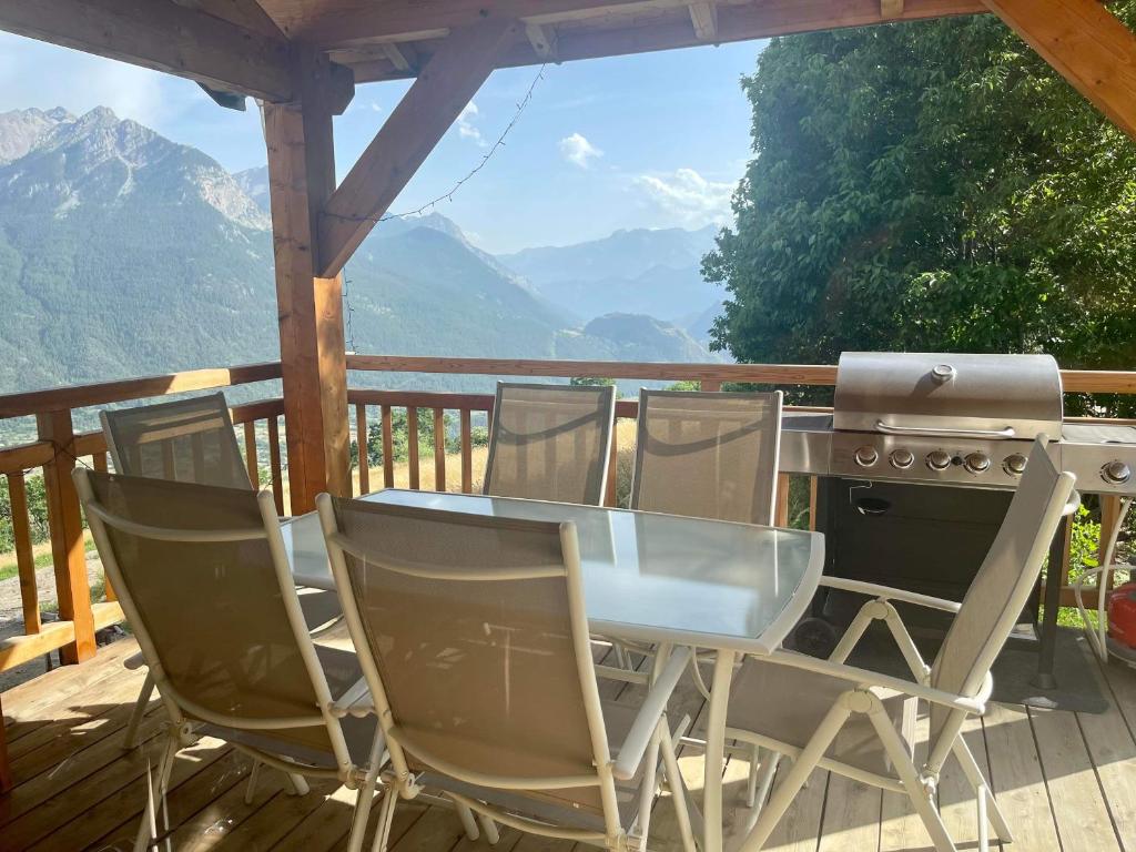 einen Tisch und Stühle auf einer Terrasse mit Grill in der Unterkunft Chalet Mariabel in Puy-Saint-Pierre