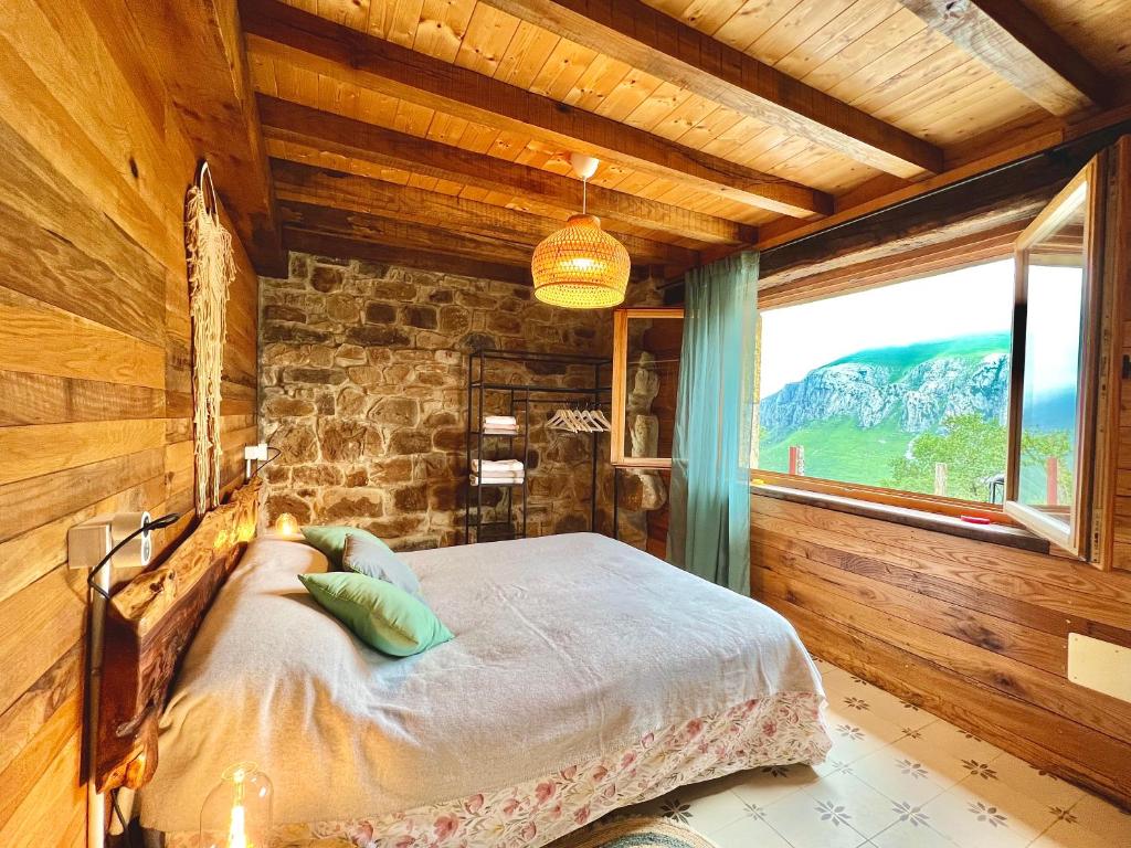 een slaapkamer met een bed en een groot raam bij La Cabaña María in San Roque de Ríomiera