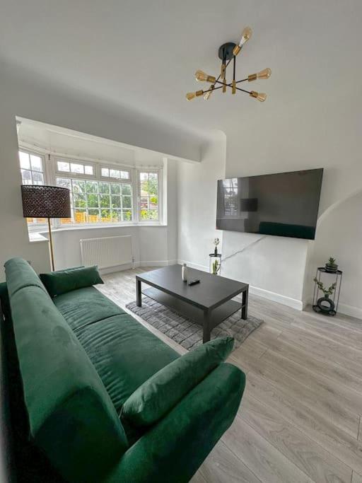uma sala de estar com um sofá verde e uma mesa em Comfortable Stay in 3 Bed House em Hither Green
