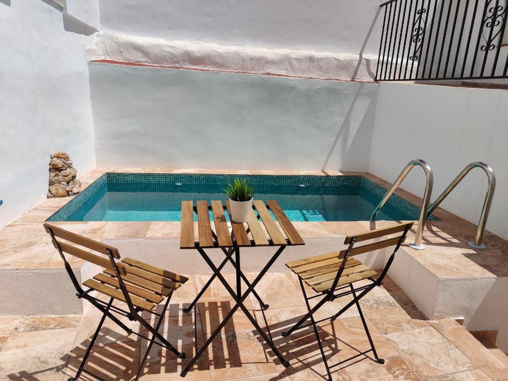 a table and chairs next to a swimming pool at Casa del Portillete in Montejaque