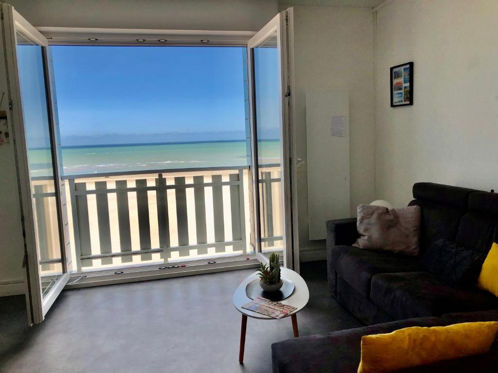 een woonkamer met een bank en uitzicht op de oceaan bij Appartement sur la plage de Malo les bains vue mer in Duinkerke