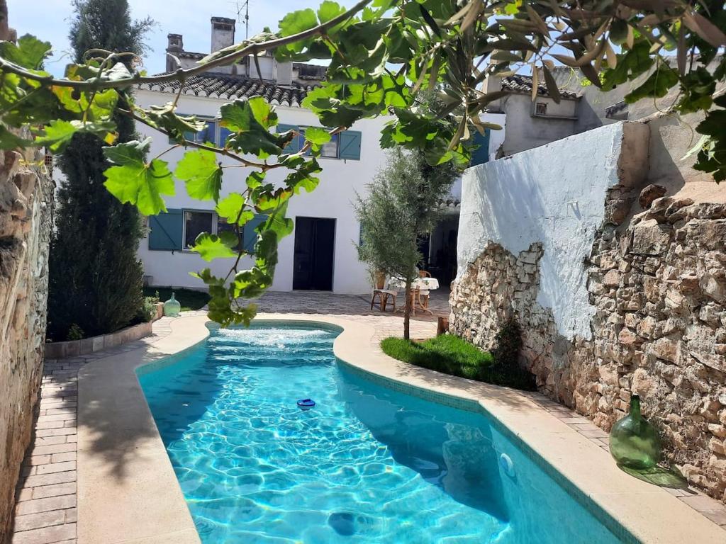 a pool in the backyard of a house with a stone wall at Las Casas del Rincón -4 dormitorios in Villahermosa