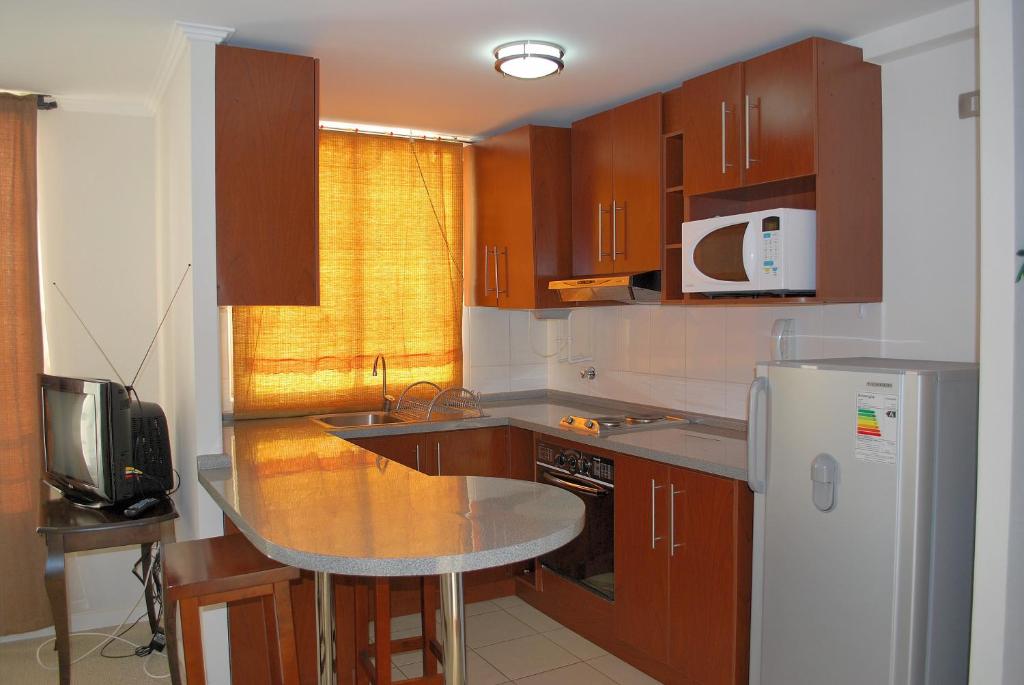 a kitchen with wooden cabinets and a white refrigerator at Apartamento Nicolás Tirado in Antofagasta