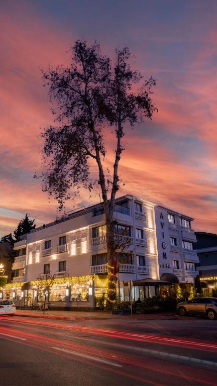 a large white building with a tree in front of it at Avion Suite Hotel in Antalya