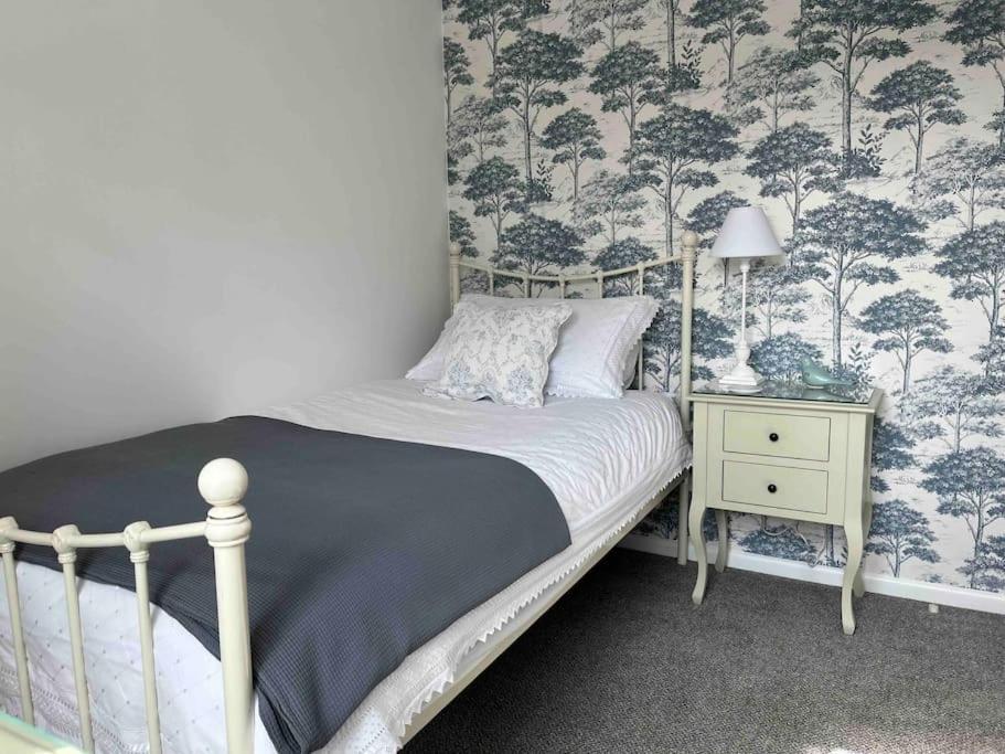 a bedroom with a bed and a table with a lamp at Escape to Ancarva Cottage near Falmouth in Perranwell