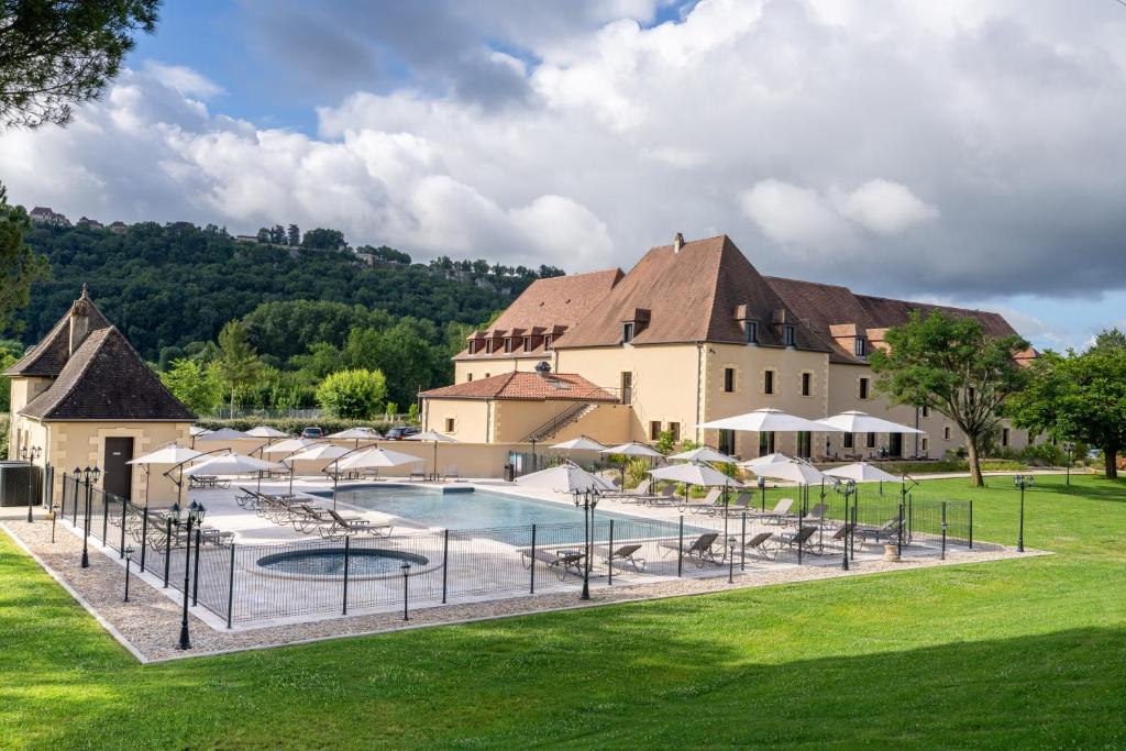 un complexe avec une piscine en face d'un bâtiment dans l'établissement Hotel Le Perigord, à La Roque-Gageac
