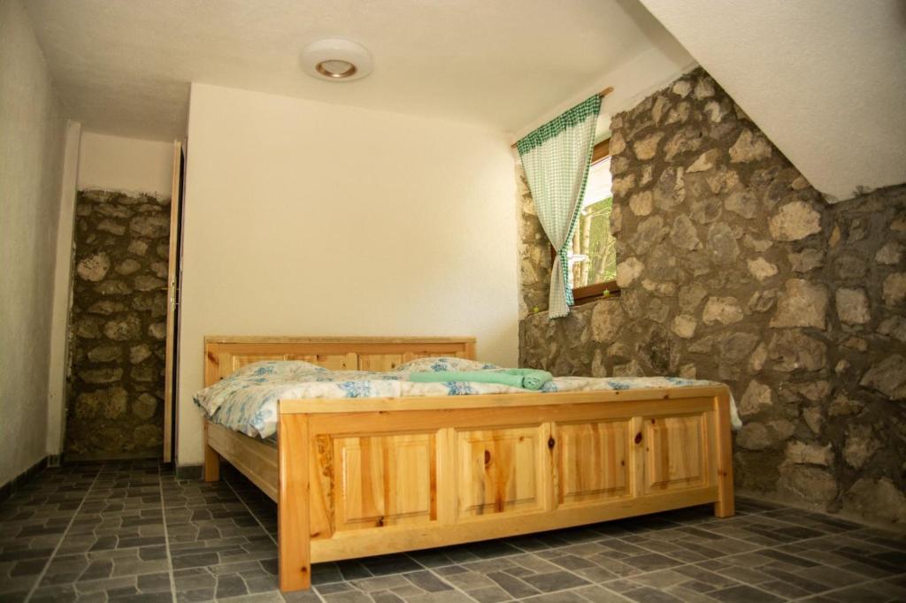 um quarto com uma cama de madeira e uma parede de pedra em Skala Resort em Gusinje