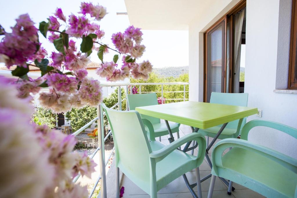 una mesa y sillas en un balcón con flores púrpuras en Flat w Nature View Balcony 1 min to Beach in Datca en Datca