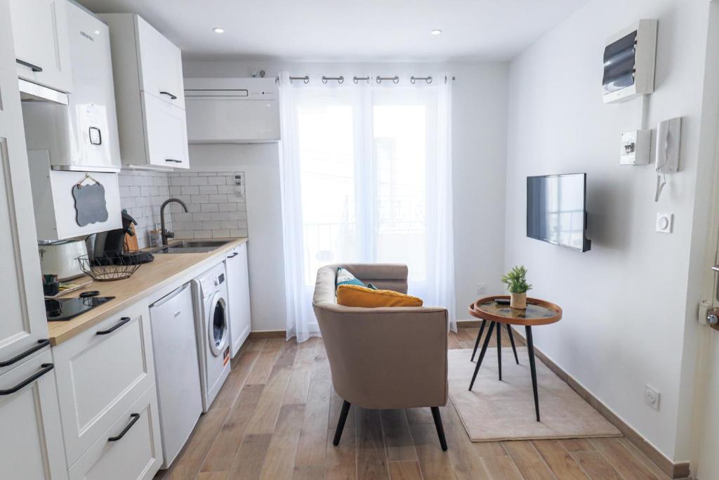 une cuisine avec des placards blancs et une table dans l&#39;établissement Charmant Studio Climatisé &#39;Alma 1&#39; - Béziers Centre - Wifi Fibre - Netflix, à Béziers