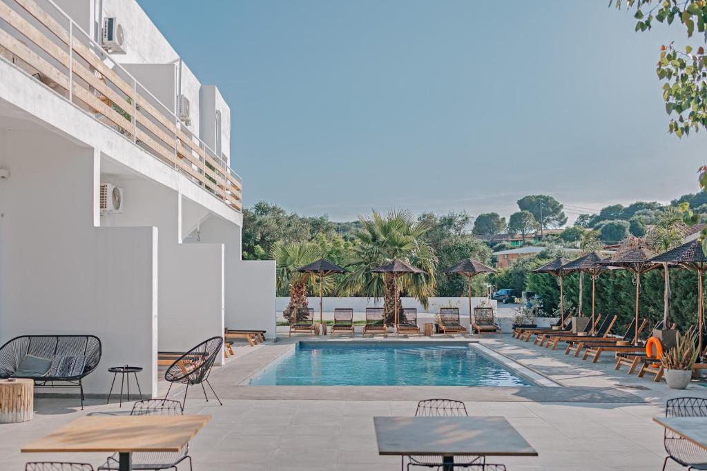 a pool at a hotel with tables and chairs at Olive Grove Suites Boutique Hotel in Moraitika