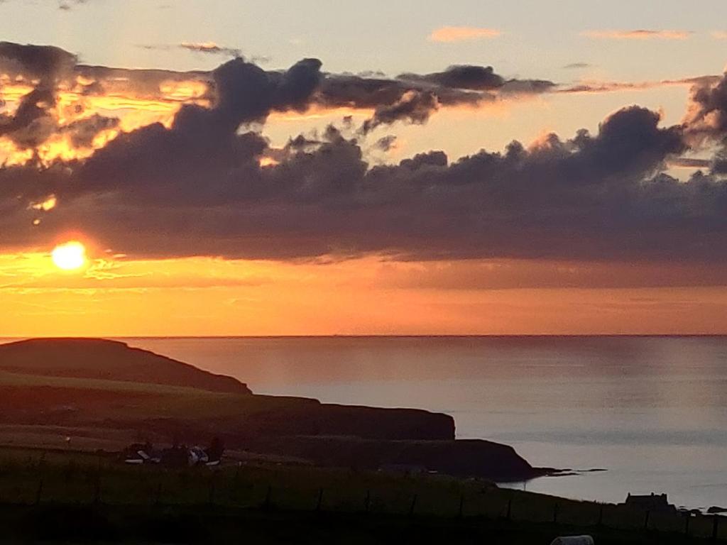 a sunset over the ocean with the sun in the sky at Mains Of Auchmedden Cottage in Pennan