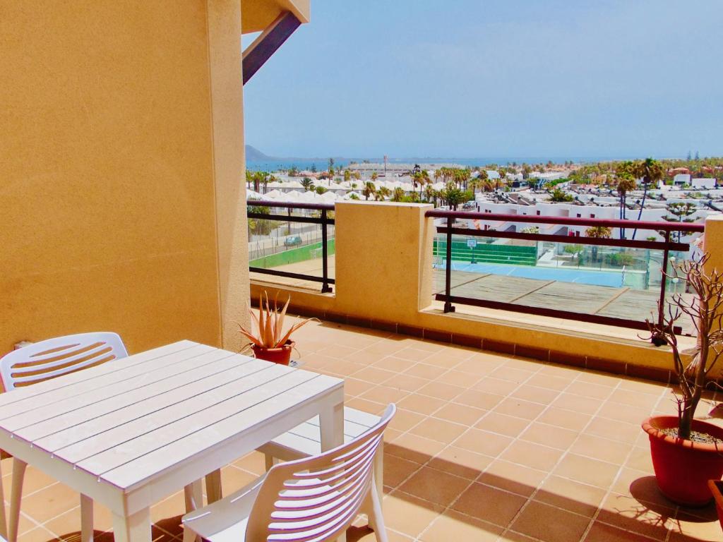 d'une table et de chaises blanches sur un balcon avec piscine. dans l'établissement El Mirador de Lobos Fuerteventura, à Corralejo