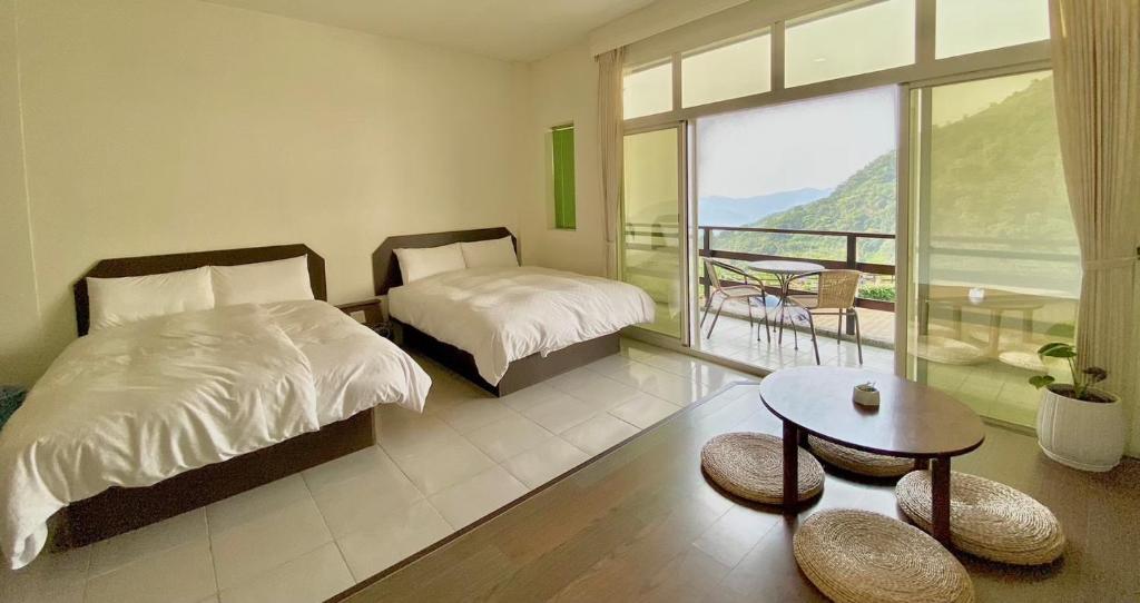 a bedroom with two beds and a table and a balcony at Mountain Lodge in Taimali