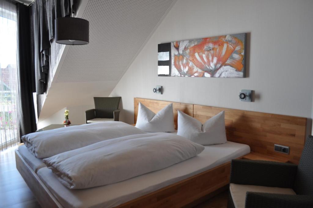 a bedroom with a large bed with white sheets at Pension Keller in Reichenau