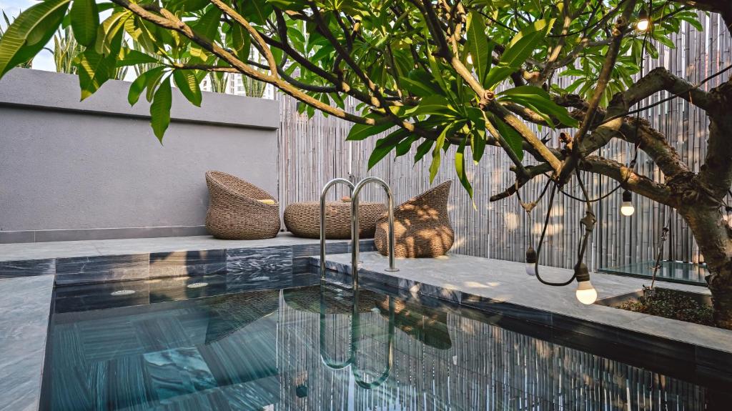 uma piscina com cadeiras ao lado de uma árvore em LAKEVIEW Park Villa - Private Pool, BBQ, Karaoke em Ho Chi Minh