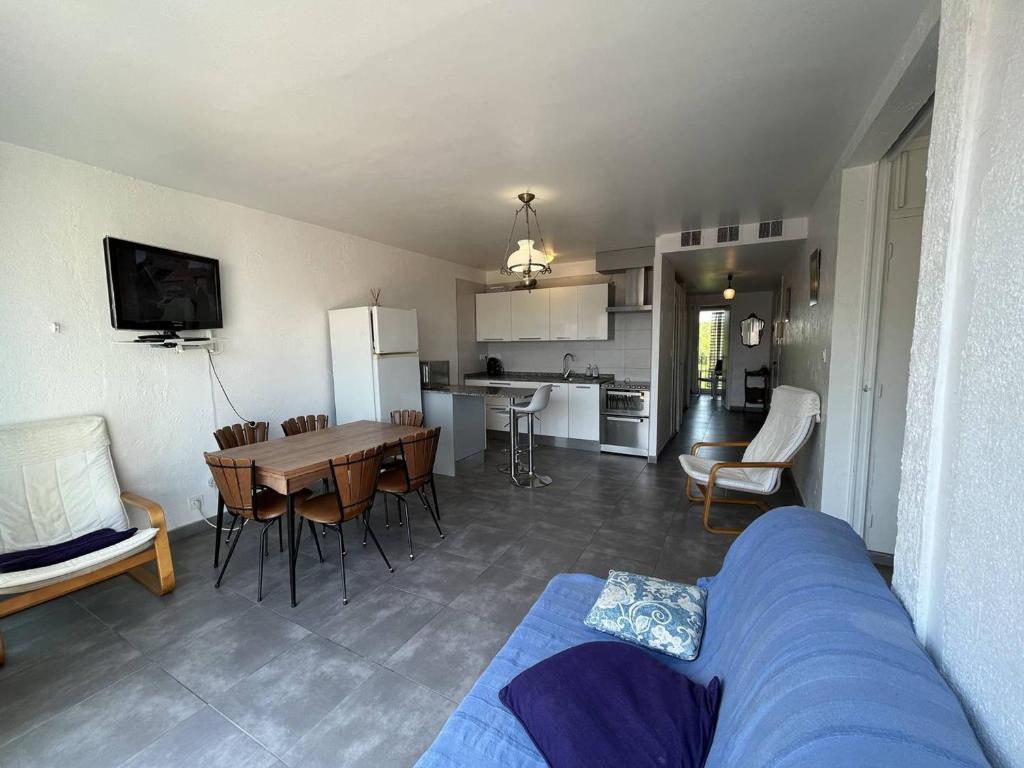 - un salon et une cuisine avec un canapé bleu et une table dans l'établissement Appartement rénové T3, 6 couchages, proche plage et commerces, parking sécurisé, animaux acceptés - FR-1-106-56, à Saint-Cyprien