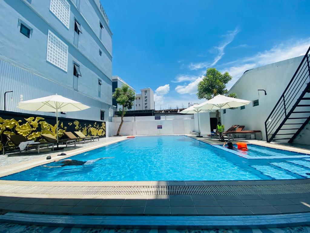 a swimming pool with chairs and umbrellas next to a building at Orchid Riverside Villa in Hue