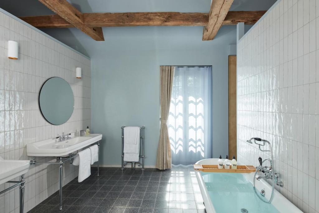 bagno con vasca, lavandino e specchio di DOMAINE LE MEZO a Ploeren