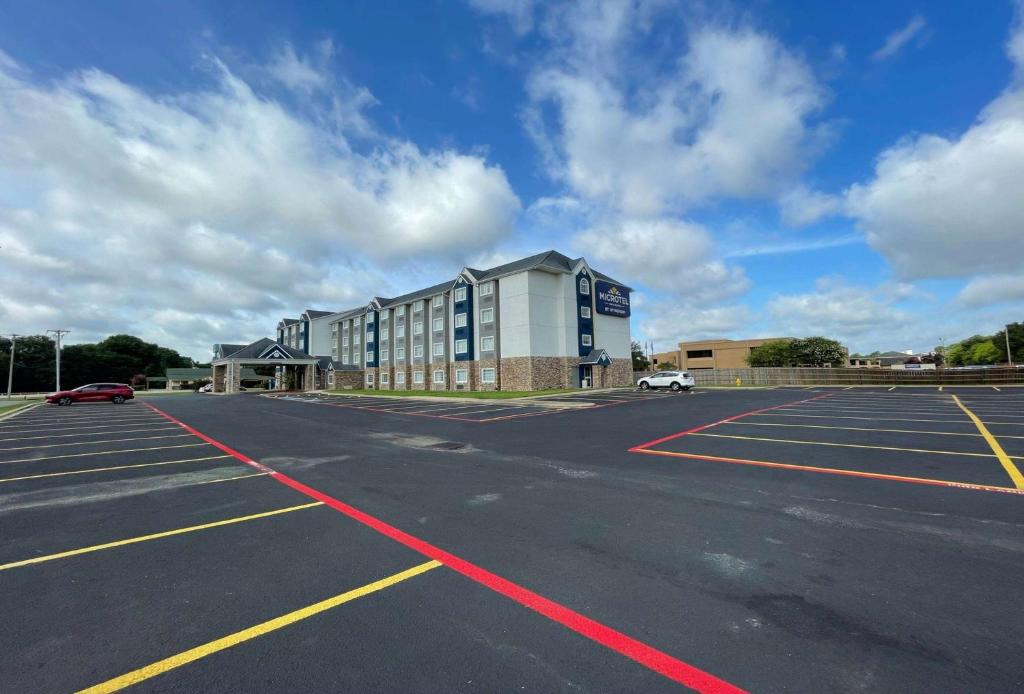 an empty parking lot with a large building at Microtel Inn & Suites by Wyndham Bossier City in Bossier City