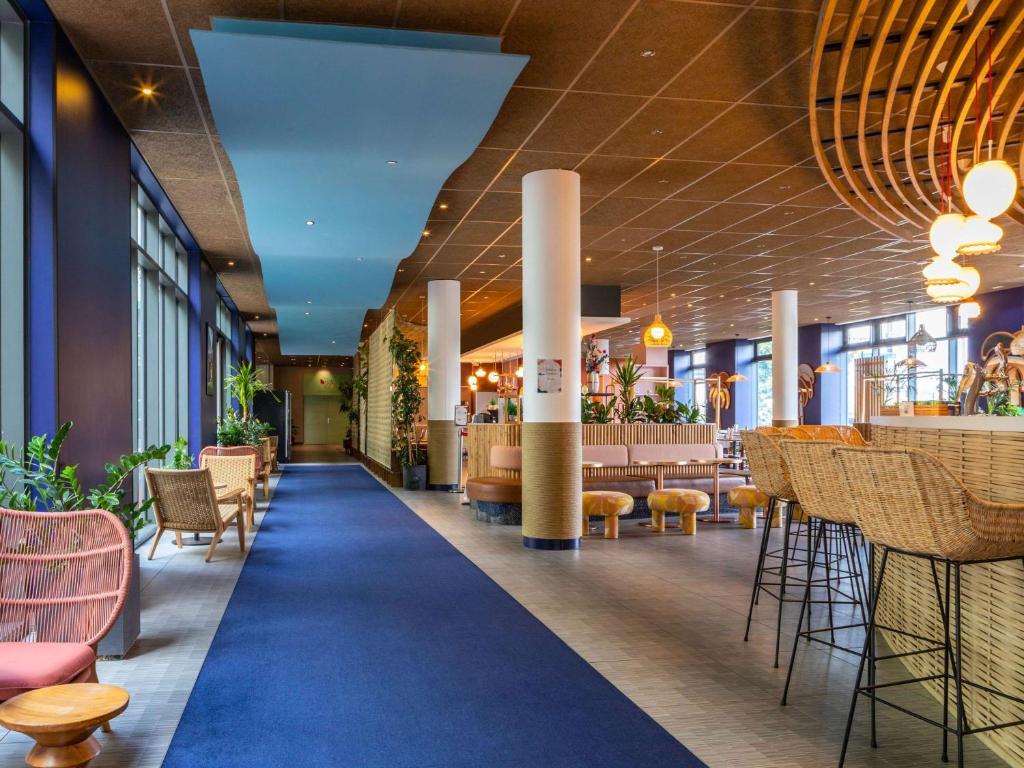 a lobby of a restaurant with tables and chairs at ibis Paris Coeur d'Orly Airport in Orly