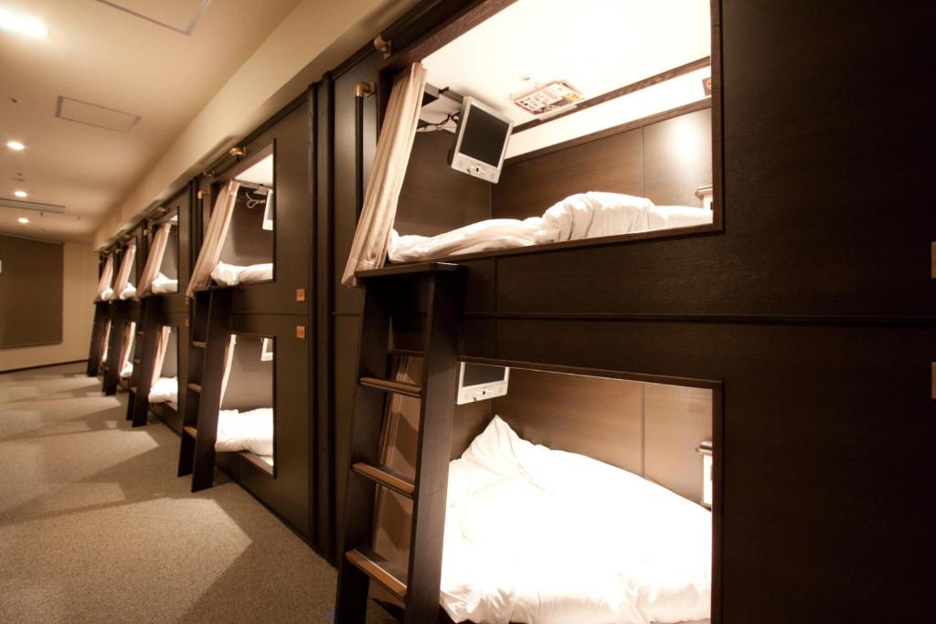 a row of bunk beds in a room at HEARTS Capsule Hotel & Spa Nakasu -Male only- in Fukuoka