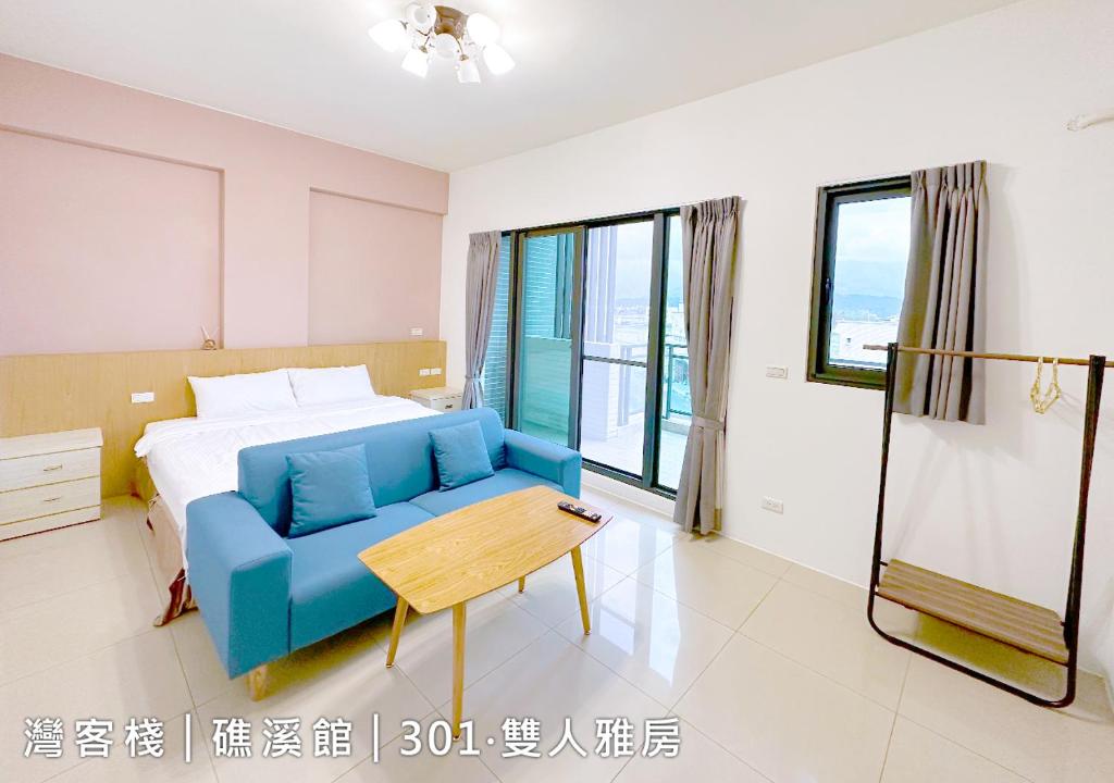 una camera con un divano blu e un letto di WeInn灣客棧 a Jiaoxi