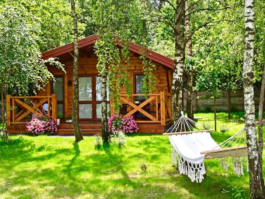 uma cabana de madeira com uma rede de descanso no quintal em Rajskie Siedlisko em Smyków