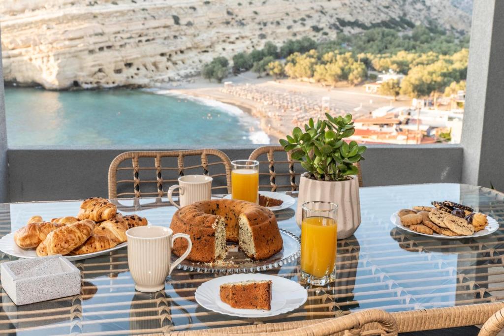 a table with a breakfast of bread and orange juice at Georgia Apartment in Matala