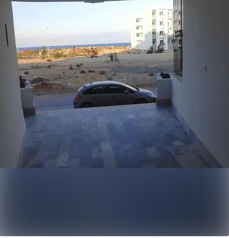a car parked in a parking lot next to a beach at Front of sea appartement hergla in Sousse