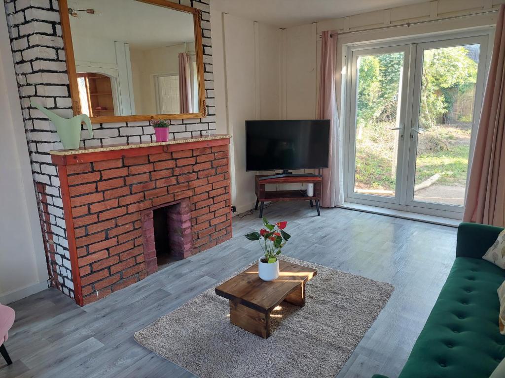 uma sala de estar com uma lareira de tijolos e uma televisão em Lovely 3 bed terraced family house em Kew Gardens
