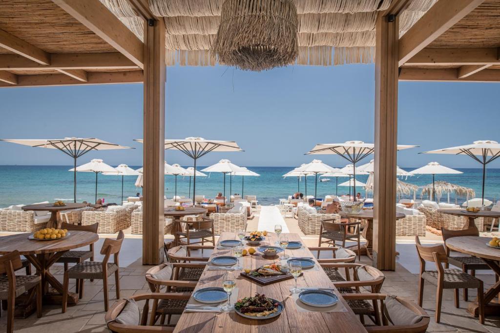 un ristorante sulla spiaggia con tavoli e sedie di Parthenis Beach, Suites by the Sea a Mália