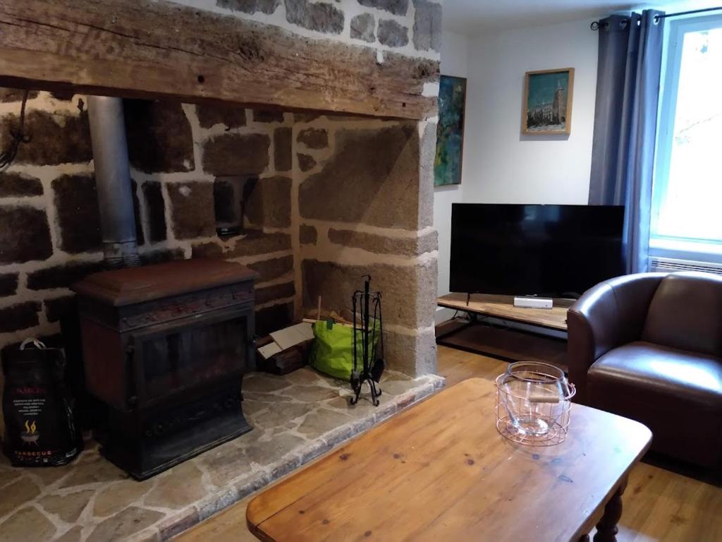 a living room with a stone fireplace and a table at Maison Village Hautefage in Hautefage