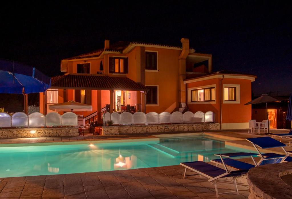 a swimming pool in front of a house at night at Piccola Locanda S'Ausentu in Uri