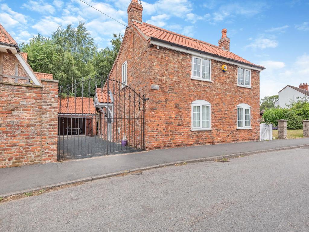 a brick house with a gate on a street at Dovedale Cottage in Coningsby