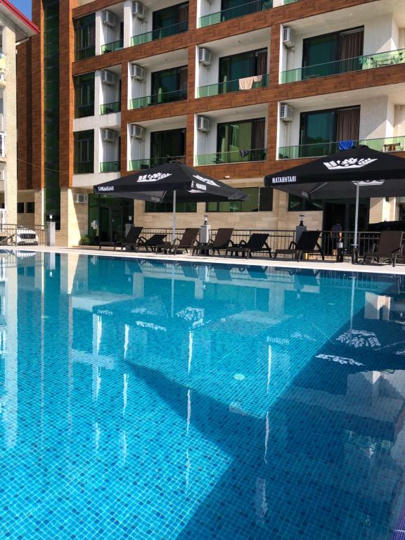 a large swimming pool with umbrellas and a hotel at Magnetiti Hotel in Ureki