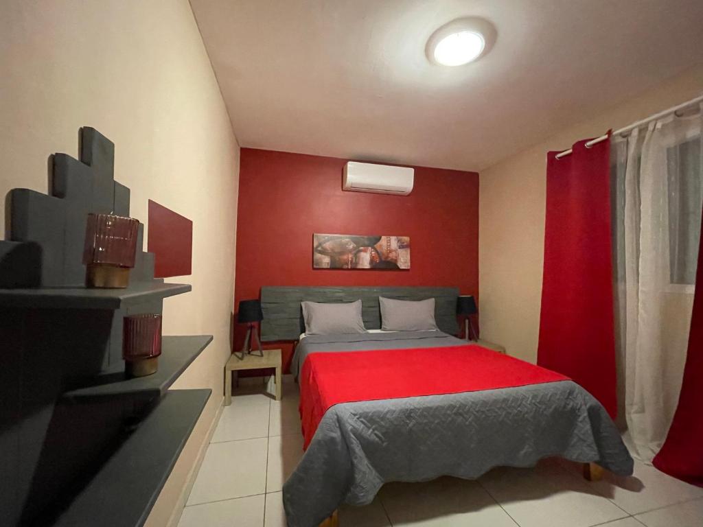 a bedroom with a bed with a red wall at Maison Villa Dagoni in Koungou