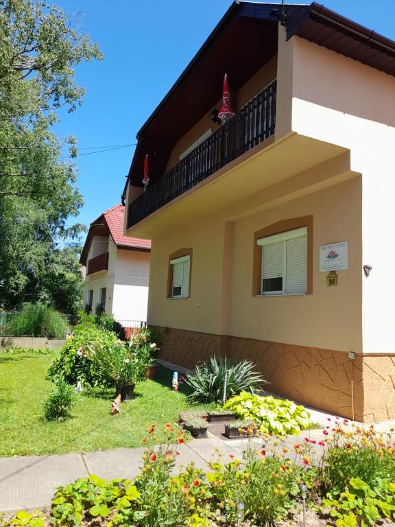 ein Haus mit einem Balkon und Blumen im Hof in der Unterkunft Tislerics Apartman in Hévíz