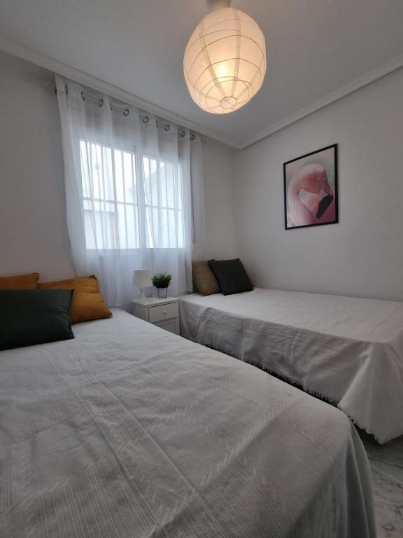 a bedroom with two beds and a chandelier at TorreSol Apartment in Torrevieja