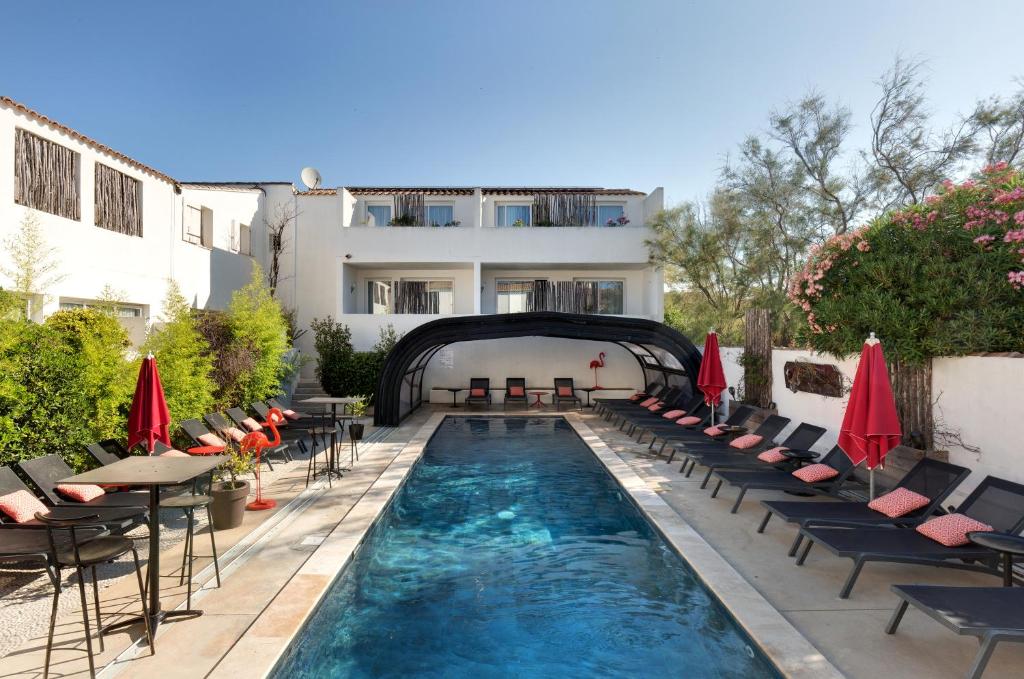 una piscina con sillas y mesas y un edificio en Vila De La Mar & Spa, en Saintes-Maries-de-la-Mer