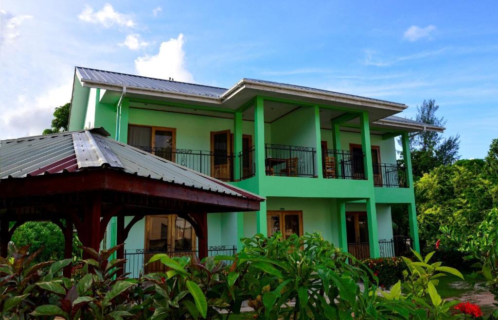 a green house with a balcony and trees at Chez Antoine Apartments in Grand Anse