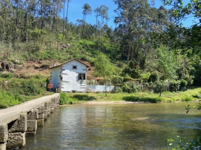 una pequeña casa junto a un río con un puente en Casa da Azenha Branca, en Castelo do Neiva