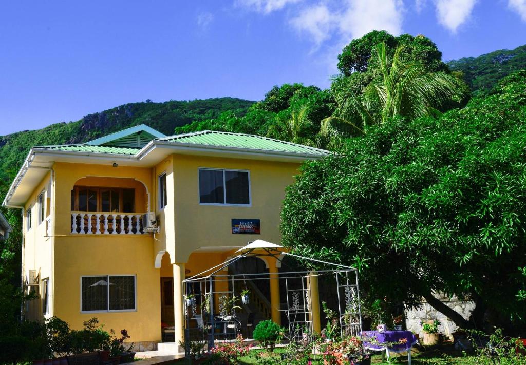 a yellow house with a green roof at Josies Cottage in Beau Vallon