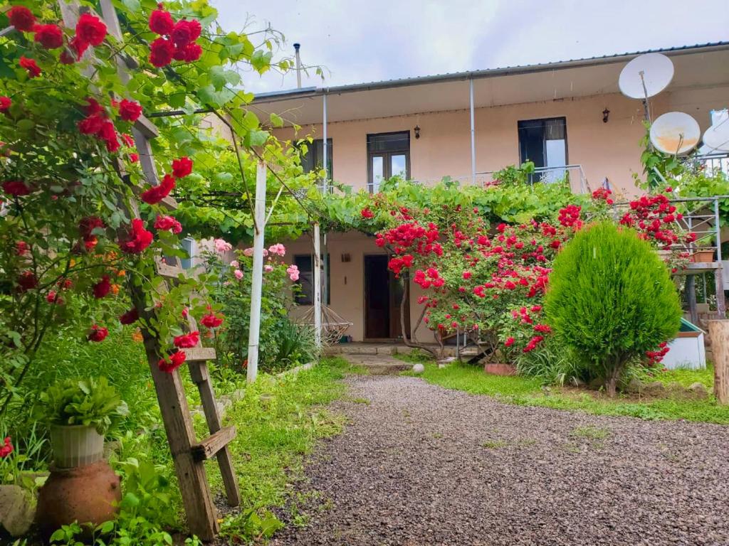 um jardim com flores vermelhas em frente a um edifício em Guesthouse Mtkvari em Nak'alak'evi