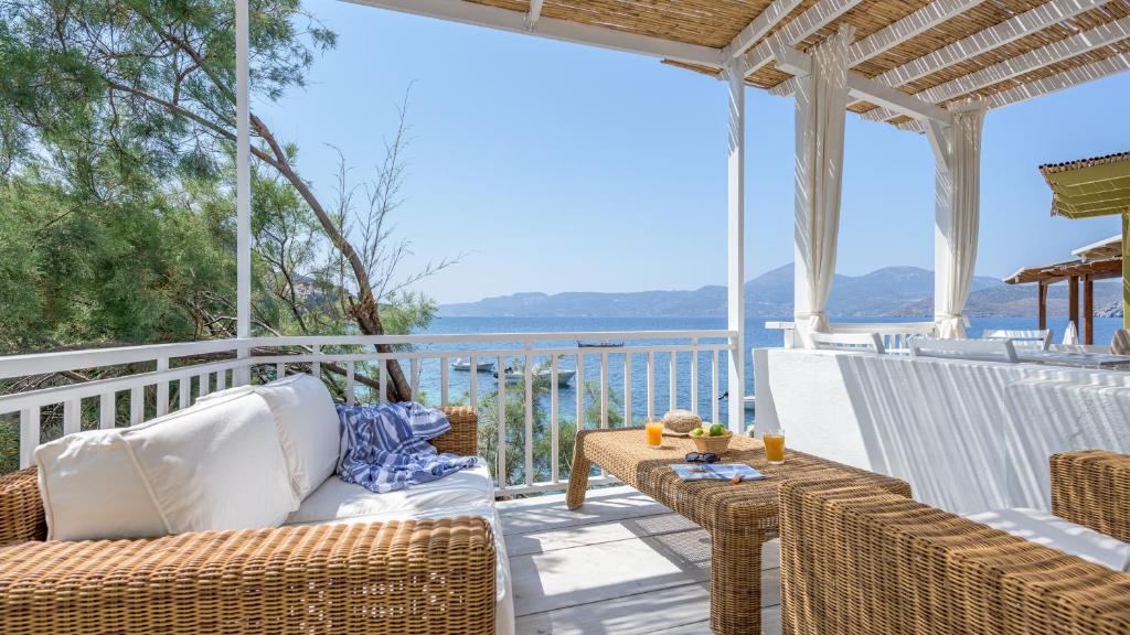 een veranda met rieten meubels en uitzicht op de oceaan bij Casa del Mar Milos in Kástron